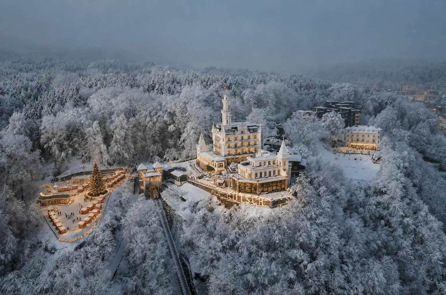 Luftbild des verschneiten Château Gütsch mit Marktdorf
